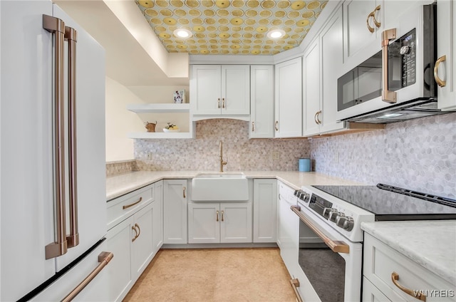 kitchen featuring high quality fridge, tasteful backsplash, sink, white cabinets, and electric stove