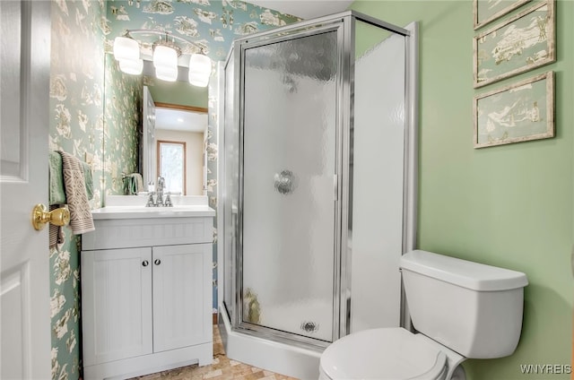 bathroom featuring vanity, a shower with door, and toilet