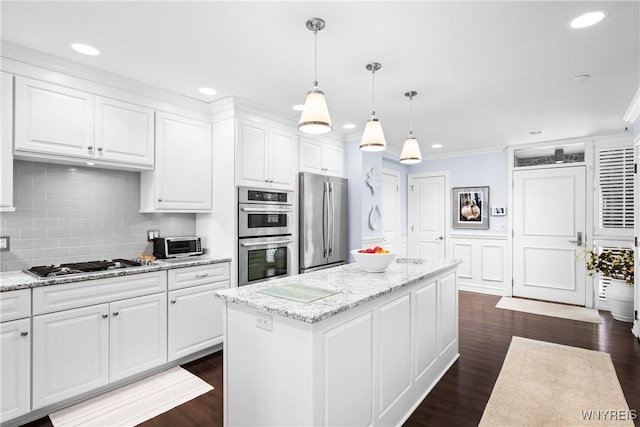 kitchen with stainless steel appliances, a kitchen island, hanging light fixtures, and white cabinets