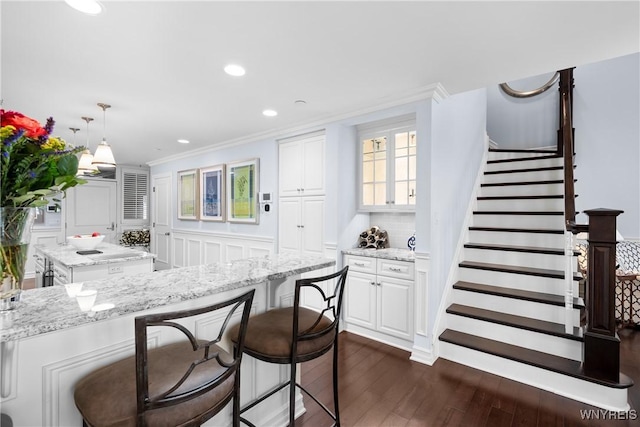 kitchen with white cabinetry, light stone countertops, a center island, and hanging light fixtures