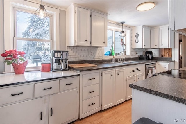 kitchen featuring white cabinetry, sink, pendant lighting, and light hardwood / wood-style flooring