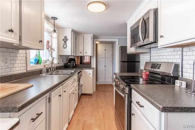 kitchen with pendant lighting, sink, stainless steel appliances, and white cabinets