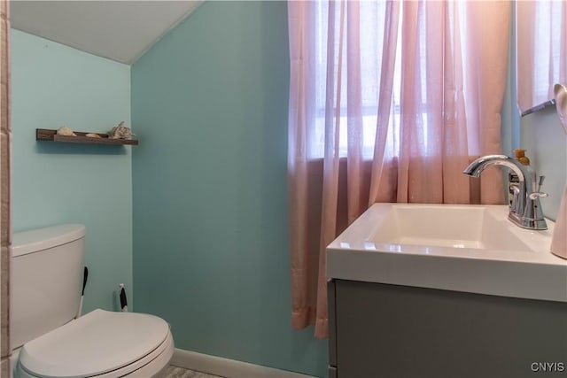 bathroom featuring plenty of natural light, toilet, and vaulted ceiling