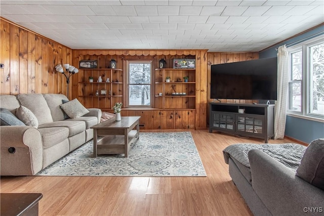 living room with crown molding, light hardwood / wood-style floors, and wood walls