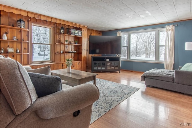 living room with a healthy amount of sunlight, wooden walls, and light wood-type flooring