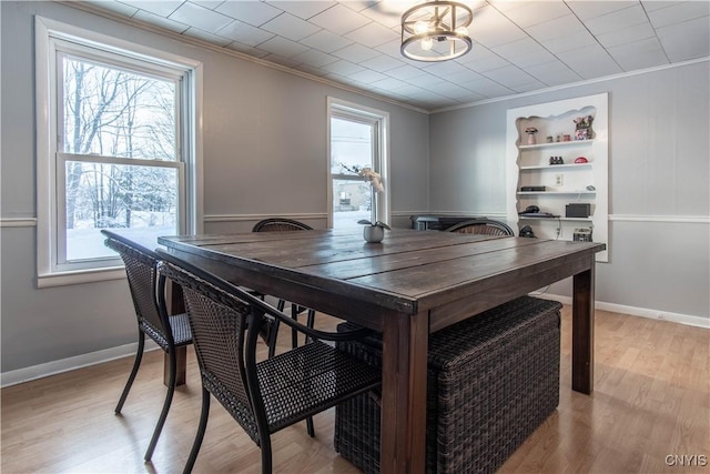 dining space with light hardwood / wood-style flooring and ornamental molding