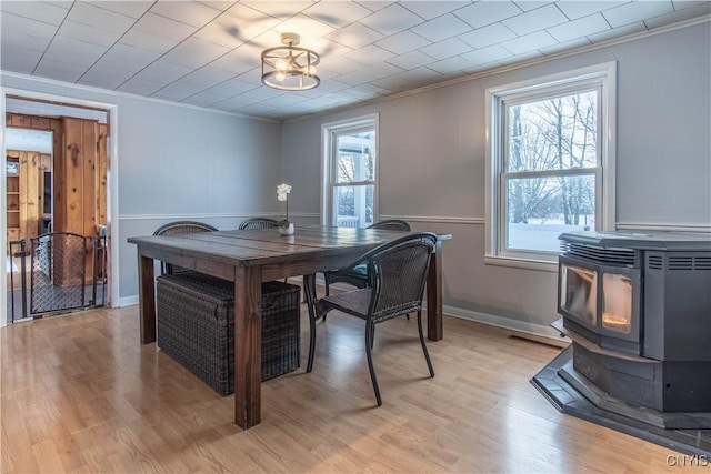 dining area featuring crown molding, light wood-type flooring, and a wood stove