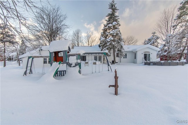 snow covered rear of property with a playground