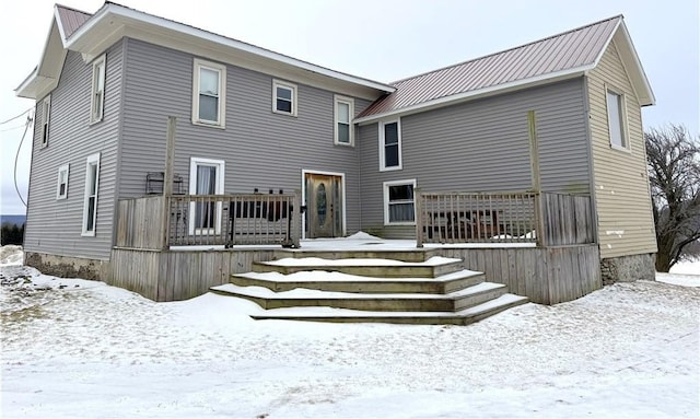 snow covered back of property featuring a deck