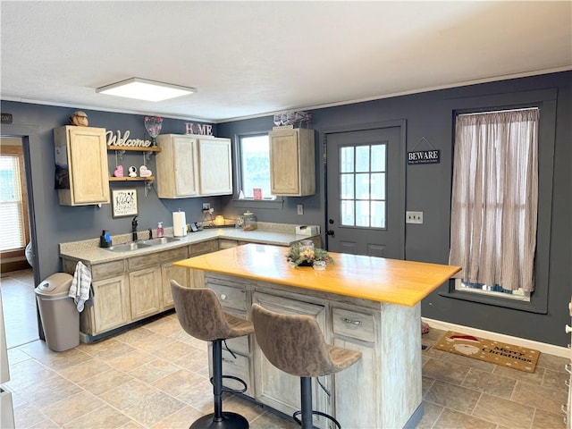 kitchen featuring a kitchen bar, sink, wooden counters, light brown cabinets, and a kitchen island