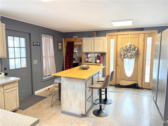 kitchen with a kitchen island, light brown cabinets, and a kitchen breakfast bar