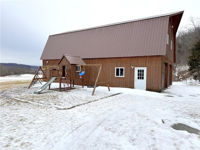 snow covered rear of property with a playground