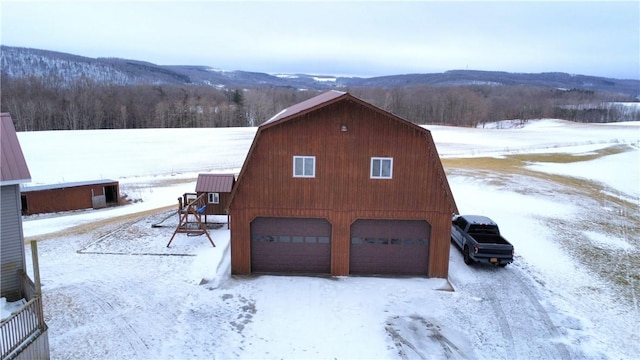 view of snowy exterior featuring a mountain view and an outdoor structure