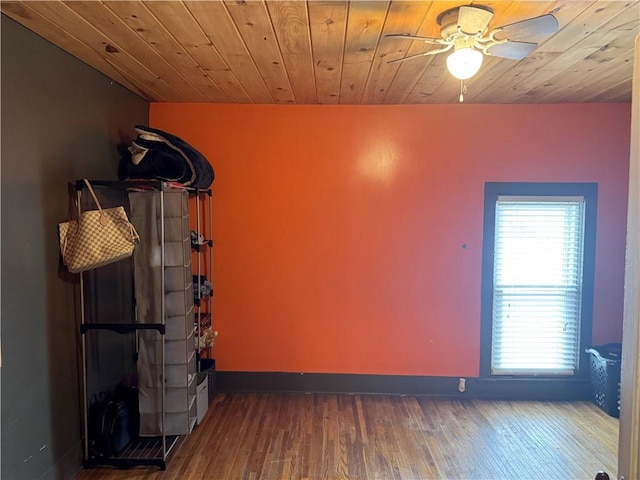 empty room featuring dark wood-type flooring, wooden ceiling, and ceiling fan