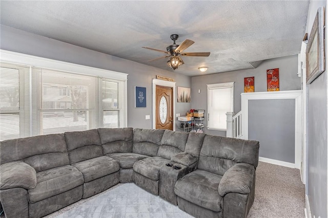 carpeted living room featuring ceiling fan and a textured ceiling