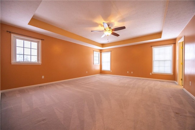 carpeted empty room featuring ceiling fan, a raised ceiling, and a textured ceiling