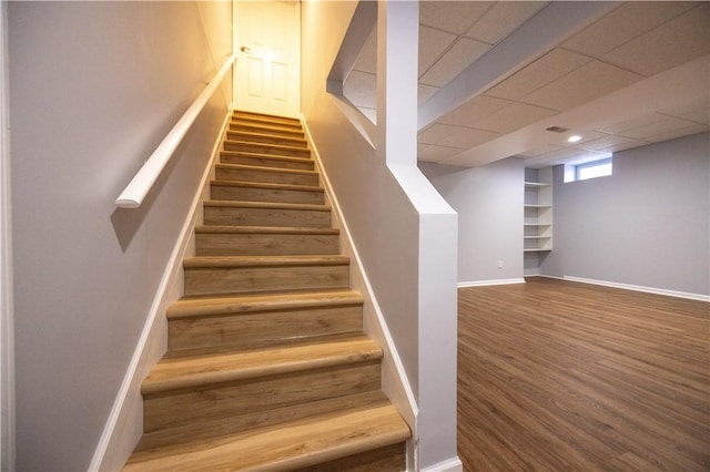 stairs with hardwood / wood-style flooring and a paneled ceiling