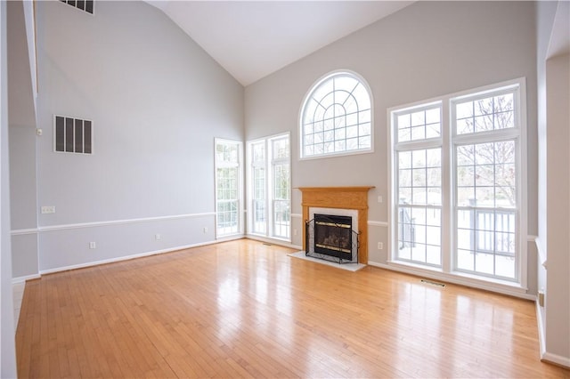 unfurnished living room with high vaulted ceiling and light hardwood / wood-style floors