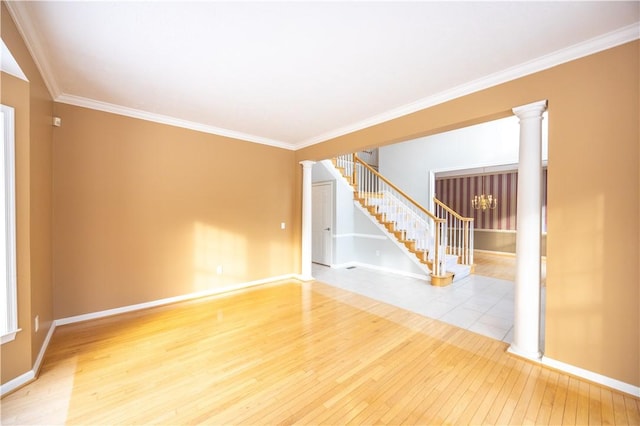 spare room with light wood-type flooring, ornamental molding, and ornate columns