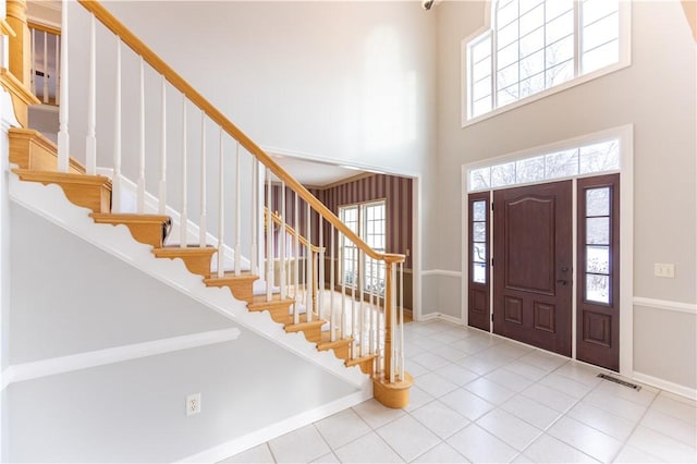 entryway featuring light tile patterned floors and a towering ceiling