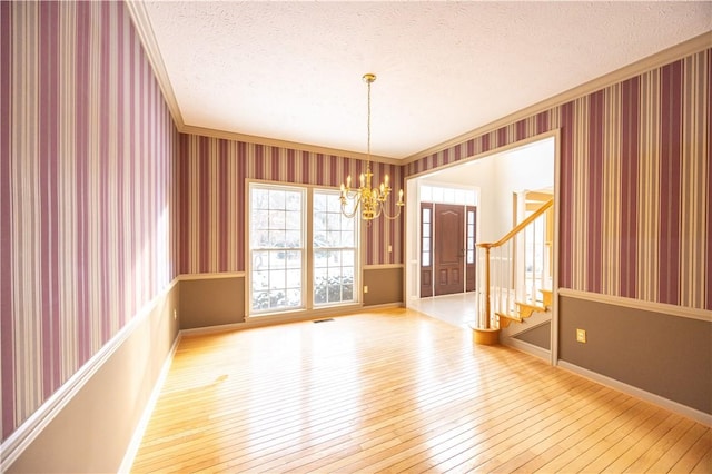 unfurnished room with crown molding, a chandelier, a textured ceiling, and light hardwood / wood-style flooring