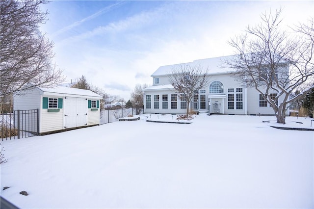 snow covered back of property featuring an outdoor structure