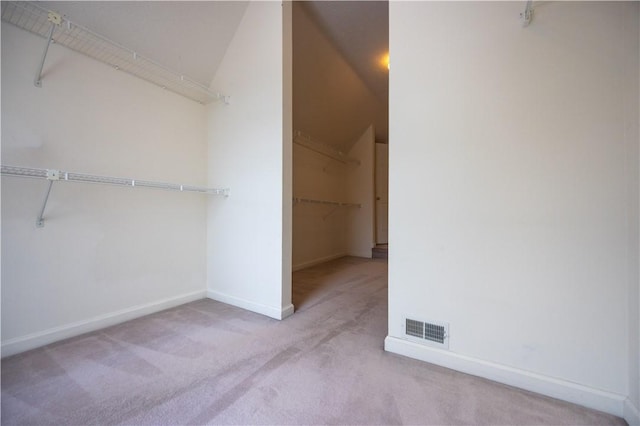 spacious closet with light carpet and vaulted ceiling