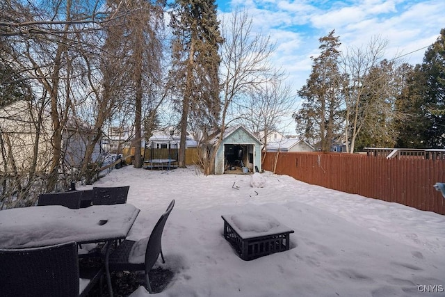 yard covered in snow with a storage unit and a trampoline