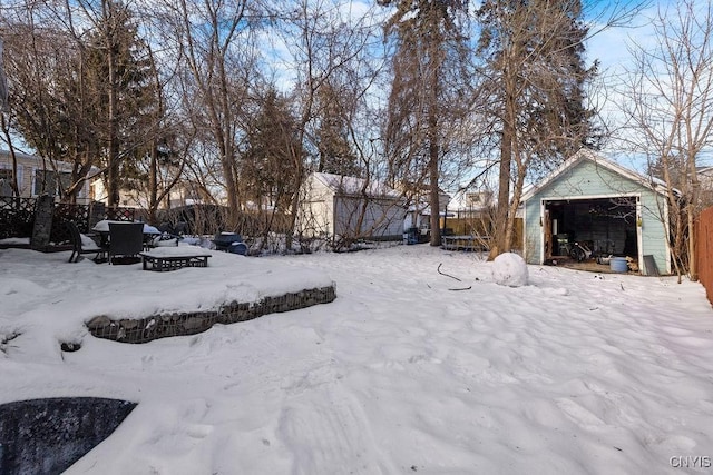 snowy yard featuring a garage and an outbuilding