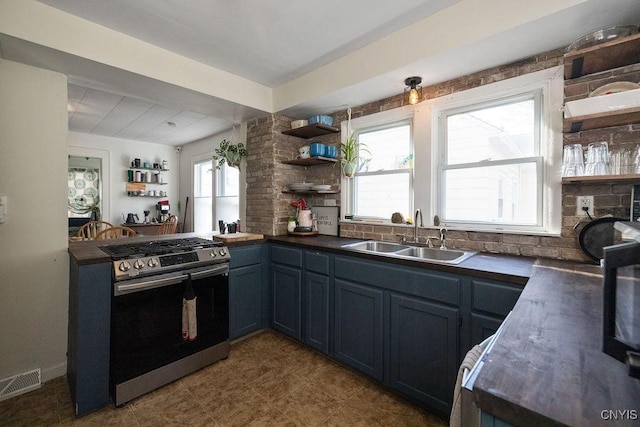 kitchen featuring sink, stainless steel gas range oven, kitchen peninsula, and blue cabinets