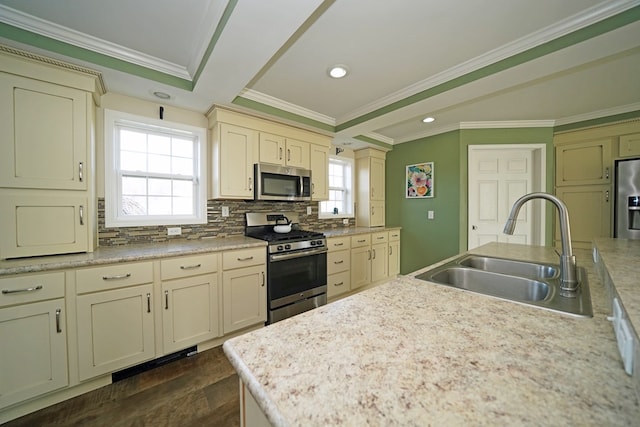 kitchen with appliances with stainless steel finishes, sink, backsplash, and cream cabinets