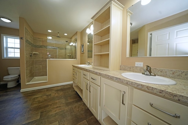 bathroom with hardwood / wood-style flooring, vanity, tiled shower, and toilet