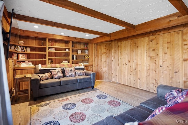 living room with hardwood / wood-style floors, a textured ceiling, beam ceiling, and wood walls