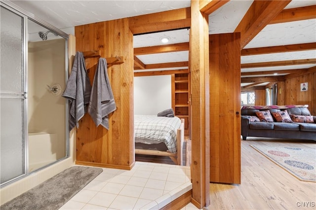 bathroom with beam ceiling, a shower with door, hardwood / wood-style floors, and wooden walls