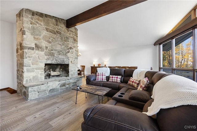 living room with lofted ceiling with beams, a fireplace, and light hardwood / wood-style flooring