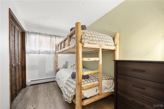 bedroom featuring a closet, baseboard heating, and light hardwood / wood-style floors