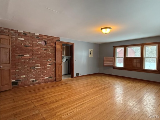 unfurnished room with brick wall and light wood-type flooring