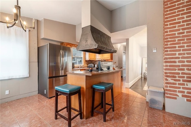 kitchen with light tile patterned flooring, a kitchen bar, tasteful backsplash, stainless steel refrigerator, and island exhaust hood