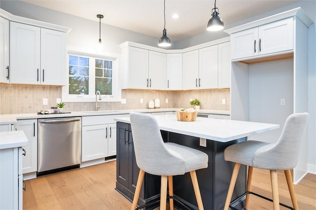 kitchen with pendant lighting, dishwasher, white cabinetry, a center island, and light hardwood / wood-style floors