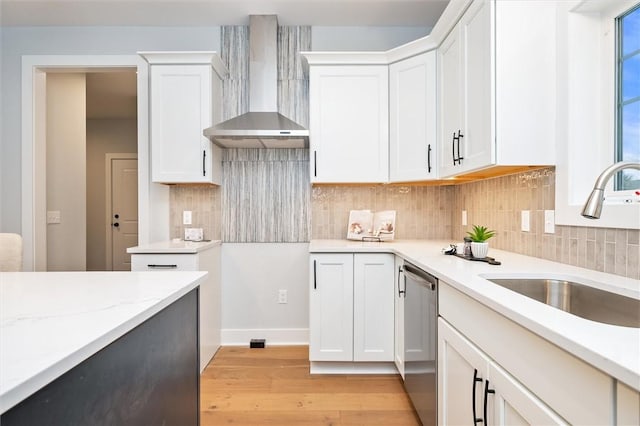 kitchen with wall chimney range hood, dishwasher, sink, and white cabinets