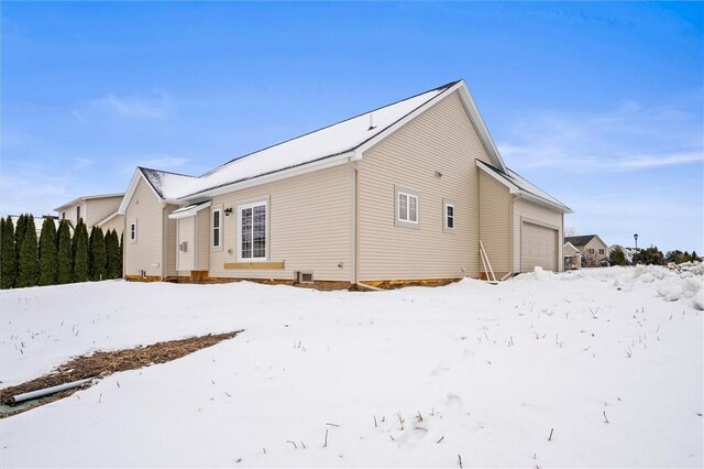 snow covered back of property featuring a garage