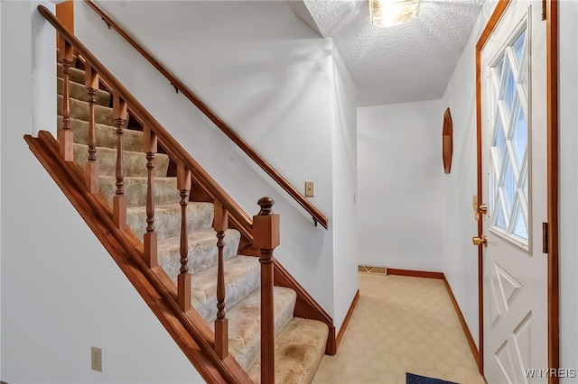 stairs featuring a textured ceiling