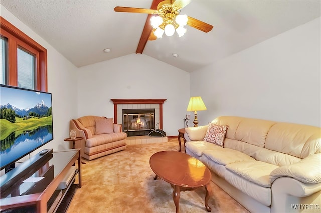 carpeted living room featuring a tiled fireplace, lofted ceiling with beams, and ceiling fan