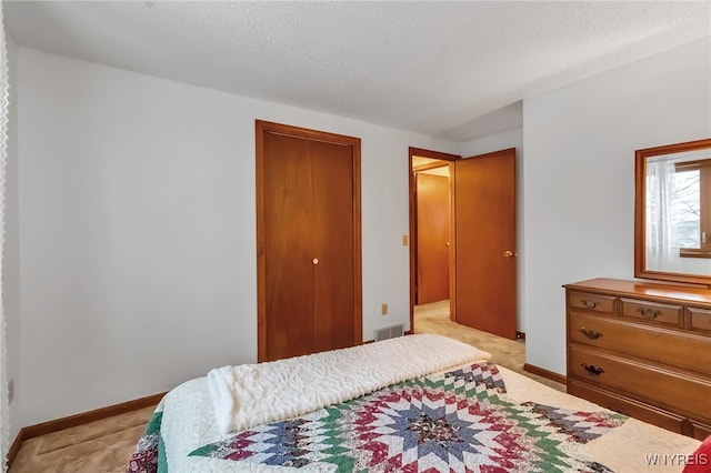 bedroom featuring light colored carpet, a textured ceiling, and a closet