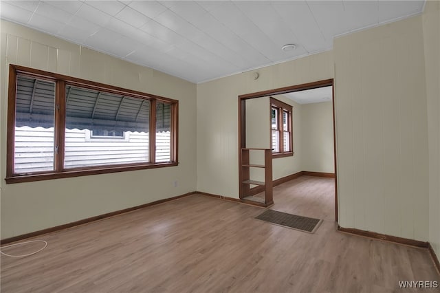 spare room featuring ornamental molding and light wood-type flooring