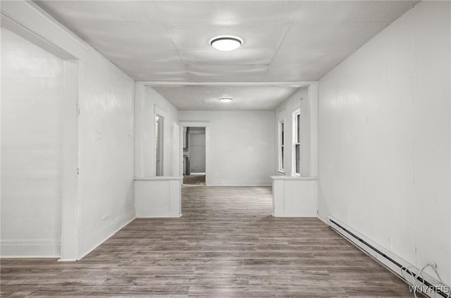 corridor with a baseboard heating unit and hardwood / wood-style floors