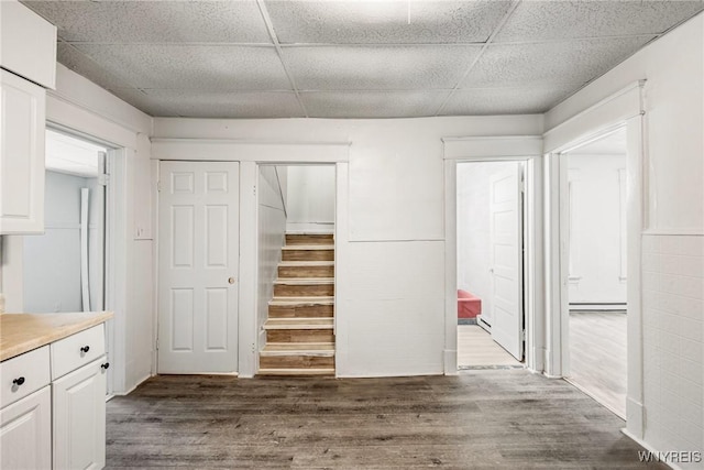 interior space featuring wood-type flooring, a baseboard heating unit, and a drop ceiling