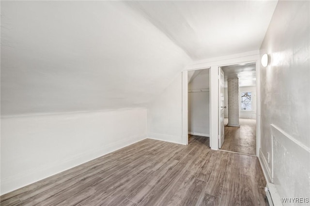 additional living space with hardwood / wood-style flooring and lofted ceiling