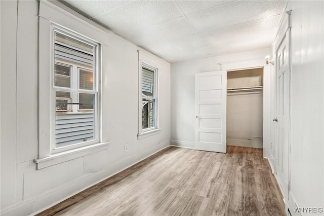 unfurnished bedroom featuring a paneled ceiling, light hardwood / wood-style floors, and a closet