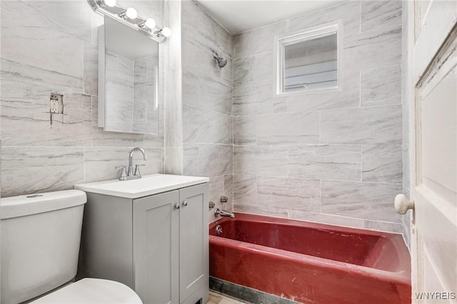 full bathroom featuring tiled shower / bath, tile walls, vanity, and toilet